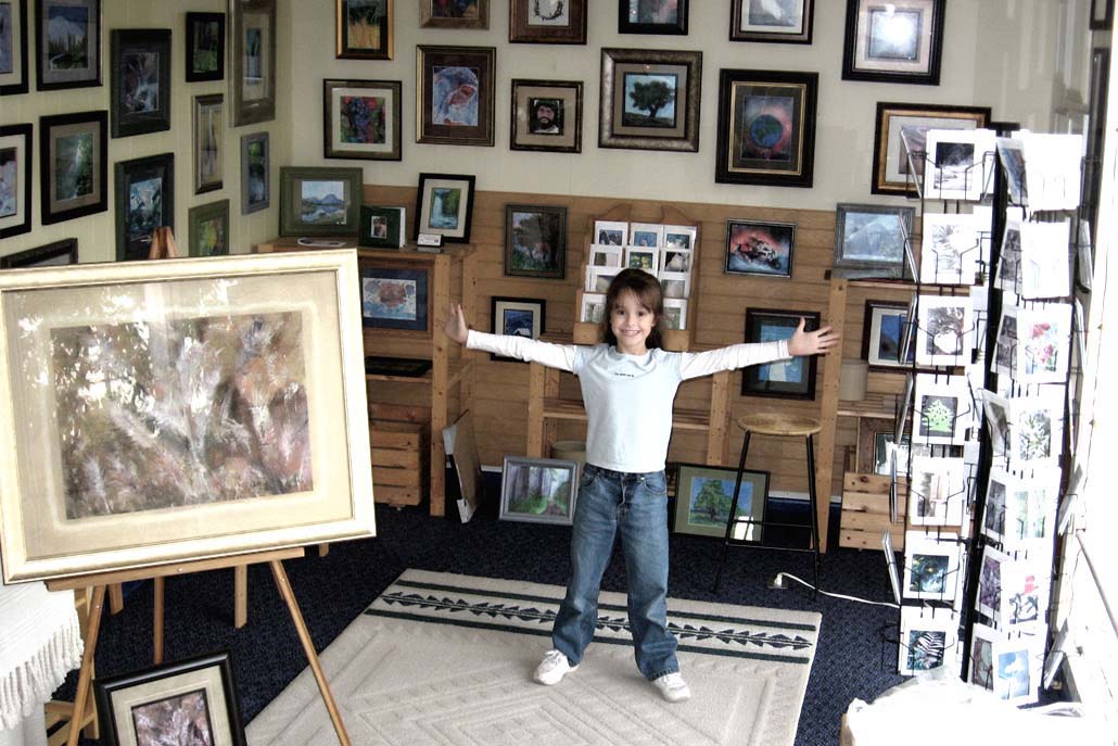 5-year-old Jordan A Cook standing in the middle of her painting gallery, arms outstretched, inviting people to come to her first open house.